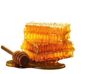 Stacked golden honeycomb pieces with dripping honey, a wooden honey dipper is on the side