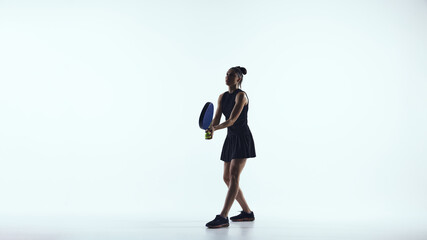 Female padel player ready position waiting for ball on white background. Concept of match readiness, reaction speed, defensive play, tactical focus, athletic control and mental concentration.