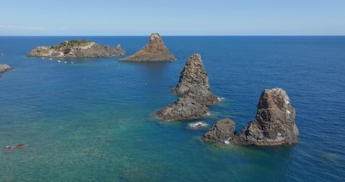 Aerial view of the Cyclopean Isles. These are small islands and basalt rocks located in the province of Catania, Sicily, Italy. In the background, on the horizon, is the Mediterranean Sea. Summer day.
