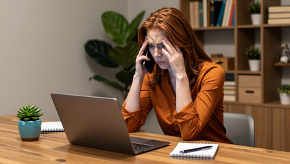 Stressed woman receiving bad news on cellphone at office