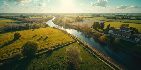Naklejka premium Green meadows in countryside near water, captured from a drone, suitable for nature documentation