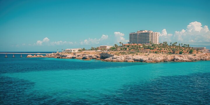 Coastal scene with resort hotels adjacent to obrava, highlighting tourism activity, set against a blue sky, holiday destination