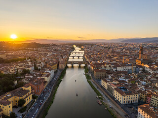 Aerial view of the Arno River snaking through the heart of the city, reflecting the golden sunset light near Ponte Santa Trinita, Florence, Tuscany, Italy.