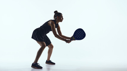 Sporty woman lunges forward hitting the ball with padel racket on white. Concept of dynamic advertising, motion-based marketing, brand action visuals, digital promotions.