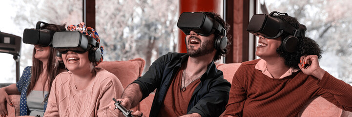 multiracial group friends wearing virtual reality glasses and with joysticks are playing dynamic game with modern graphics