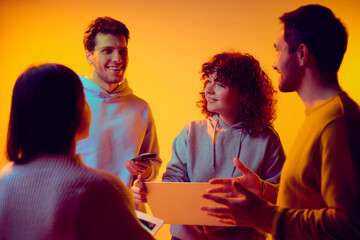 Group of colleagues discussing tasks and timelines together under neon light. Concept of project...
