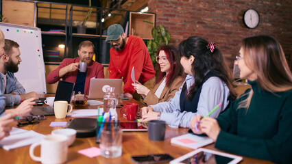 Diverse coworkers discussing ideas during creative office meeting. Concept of teamwork communication, collaborative decision making, startup culture and modern coworking workspace.