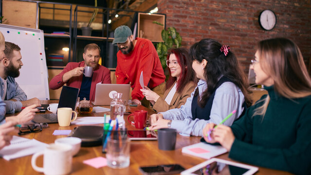 Diverse coworkers discussing ideas during creative office meeting. Concept of teamwork communication, collaborative decision making, startup culture and modern coworking workspace. - Powered by Adobe