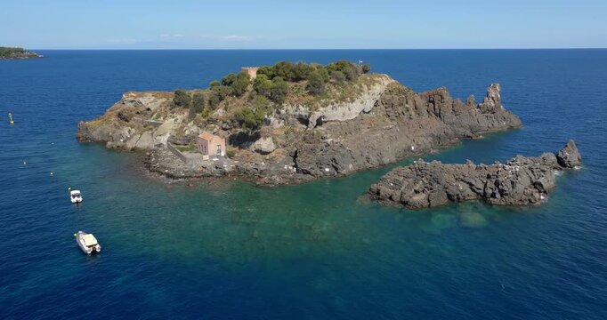 Aerial view of the Cyclopean Isles. These are small islands and basalt rocks located in the province of Catania, Sicily, Italy. In the background, on the horizon, is the Mediterranean Sea. Summer day.