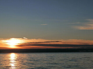 Sunset over the sea, the sun sets into the clouds behind the horizon