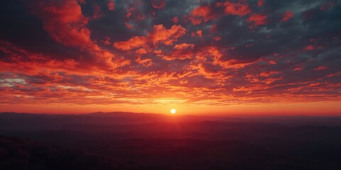 Fototapeta premium Sunset with vibrant red sky and dynamic cloud formations across rolling hills and mountain terrain, highlighting natural scenery