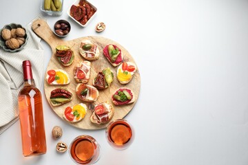 Tasty bruschettas with prosciutto and rose wine served on white table, flat lay. Space for text