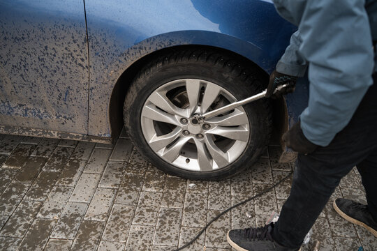 A man tightens wheel nuts with a torque wrench