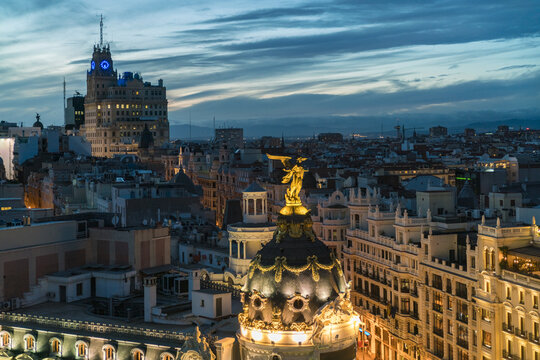 Aerial view of Metropolis Building gleaming under the twilight sky, with the Telefonica Building standing tall in the distance, Madrid, Community of Madrid, Spain.