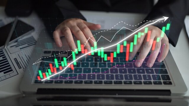 A businessman analyzes digital financial data on a laptop, surrounded by stock market graphs and charts showcasing trends and growth in finance and investment. Copula - Powered by Adobe