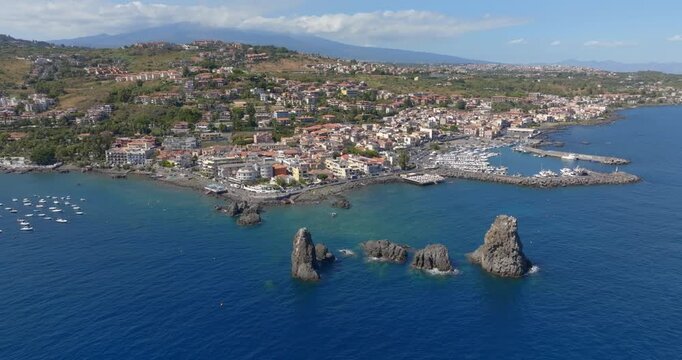 Aerial view of the town of Aci Trezza overlooking the Ionian Sea, in the province of Catania, Sicily, Italy. In the foreground, off the coast, are the Cyclopean Isles. In the background is Mount Etna.