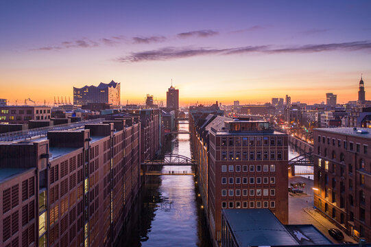 Aerial view of the Speicherstadt's red-brick warehouses meet the Elbphilharmonie's shimmering glass under a pastel sky, Hamburg, Hamburg, Germany.