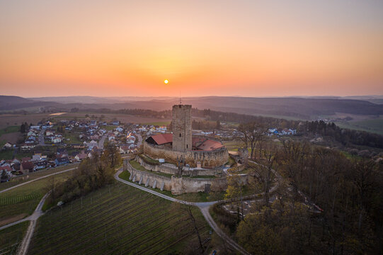 Aerial view of Burg Steinsberg bathed in the warm glow of the setting sun, its ancient stones contrasting with the verdant vineyards below, Sinsheim, Baden-Wurttemberg, Germany.
