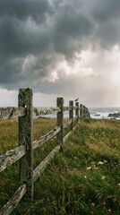 Fototapeta premium Stormy Sky Over Coastal Fence with Grass and Ocean View