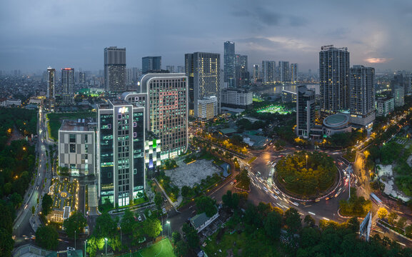 Aerial view of city buildings and roundabout with streaking lights under a dusky sky, Hanoi, Vietnam.