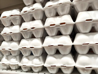 Stack of fresh brown eggs in white styrofoam carton package on shelf. Grocery store product display for food shopping concept.