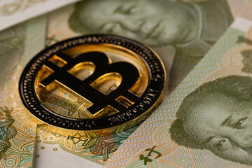 Golden Bitcoin Physical Coin on Chinese Yuan Banknotes Background Macro