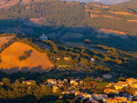 Aerial view of golden light bathing the rolling hills and the charming town nestled below, a Tuscan dreamscape of warmth and tranquility, Saturnia, Tuscany, Italy.