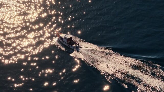 Aerial drone view of a small motorboat speeding across the water, leaving a white foamy trail behind it on the calm turquoise sea. Biograd na Moru, Croatia