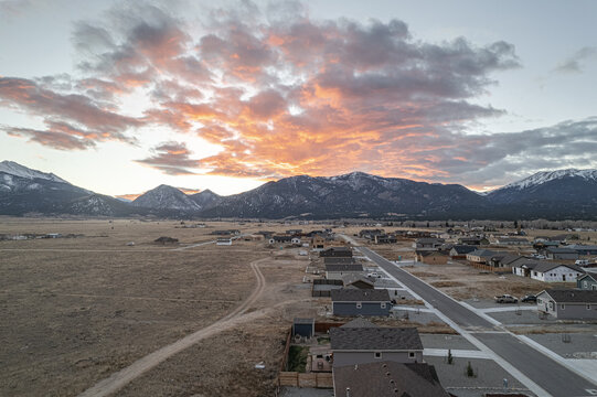Aerial view of a tranquil town nestled beneath snow-dusted mountains as the sky blazes with fiery hues at sunset, Buena Vista, Colorado, United States.