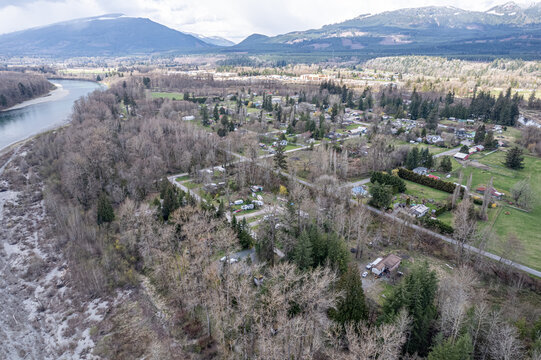 Aerial view of a river snaking past a small town nestled among trees, with mountains rising in the distance, Hamilton, Washington, United States.