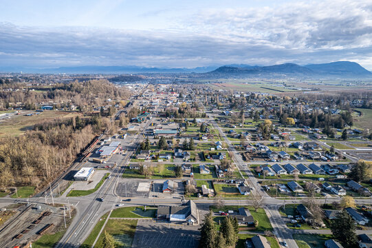 Aerial view of the town nestled amidst a tapestry of greens and browns, with the Cascade Mountains standing guard in the distance, Sumas, Washington, United States.