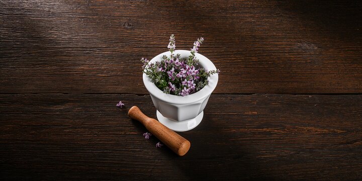 Thyme flowers in a mortar on dark wood surface, herbal preparation for culinary use