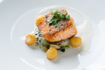 Salmon fillet dish with potatoes, vegetables, and foam sauce
