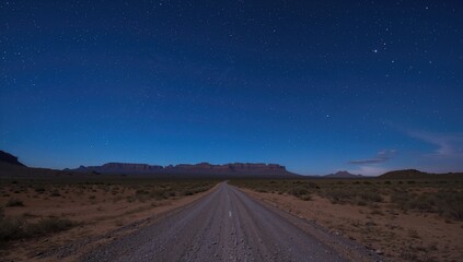 Starry sky over a wasteland during long exposure, showing a gravel road leading to mountain ranges on the horizon, highlighting rural accessibility