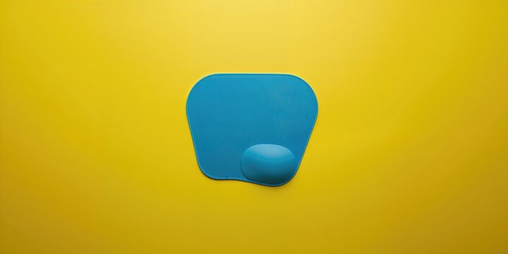 Flat lay of a sleek blue mousepad for computer setup with copy space on a bright yellow surface
