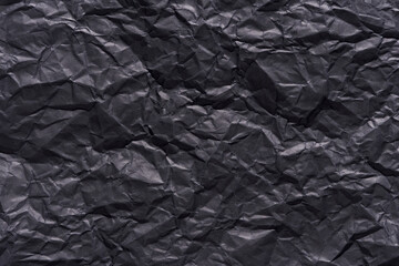 Crumpled black paper texture background for creative design and art projects.