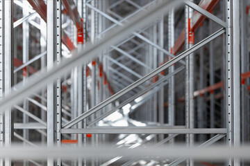 Close-up view of industrial metal shelving racks in a warehouse or factory. The steel structure with orange beams and metal efficient storage system. Logistics industrial design concepts