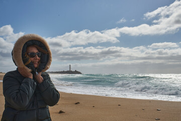 Woman enjoying windy winter day at beach with lighthouse