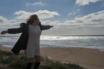 Woman enjoying freedom by the sea on a windy beach