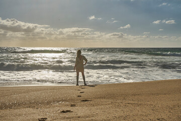 Woman standing on beach looking at ocean waves