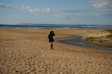 Woman walking on empty winter beach contemplating ocean