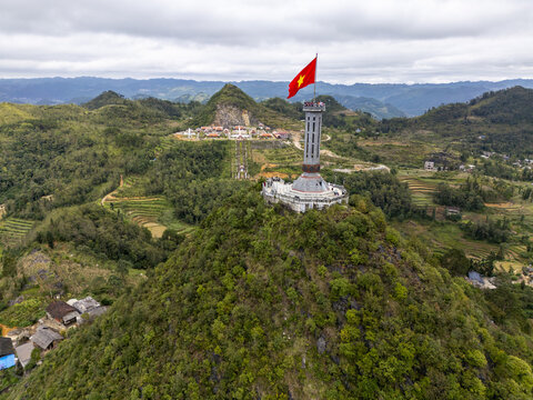 Aerial view of the Lung Cu Flag Tower stands tall, a beacon amidst a verdant landscape under a cloudy sky, a symbol of national pride, Lung Cu, Tuyen Quang, Vietnam.