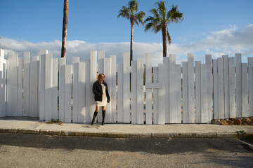 Woman standing by white fence with palm trees