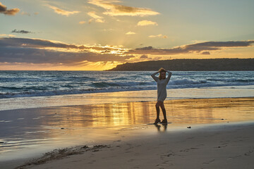 Woman enjoying sunset on beach during golden hour