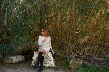 Young woman sitting on rock smiling, wearing sunglasses