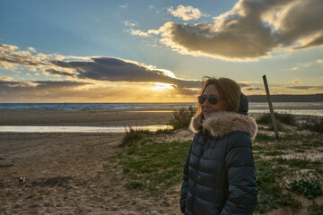 Woman contemplating sunset on a winter beach