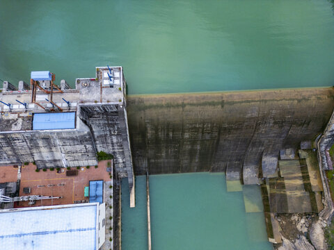 Aerial view of water cascading over a concrete dam, its stark texture contrasting with the smooth, turquoise water below, Long Phu, Soc Trang, Vietnam.