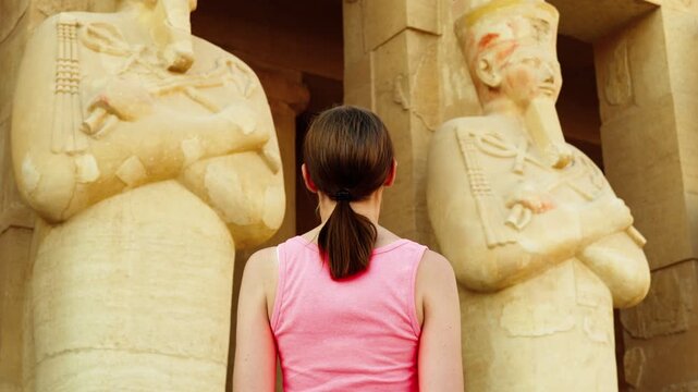 A female tourist looks at the Statues of Queen Hatshepsut in the form of Osiris on the upper terrace of the temple of Hatshepsut in Luxor, Egypt.