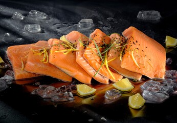 Fresh, vivid salmon, seasoned with herbs and lemon, rests among shimmering ice crystals. The dark, reflective surface below enhances the bright colors © Damian