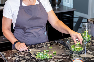 A woman chopping and preparing Brussels Sprouts for cooking.